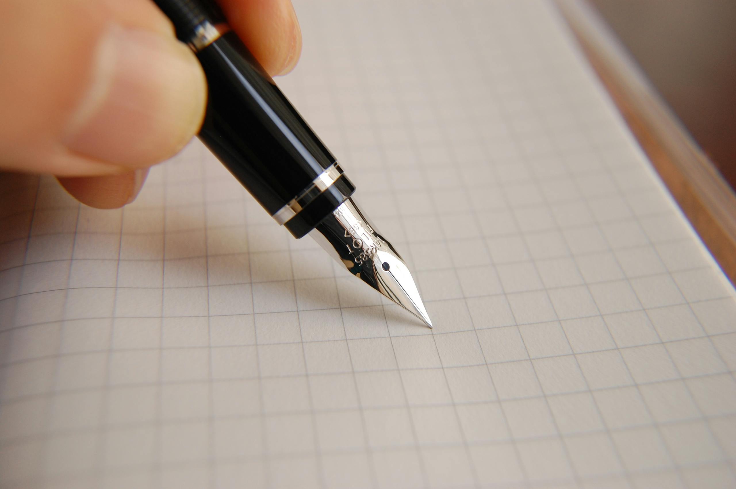 A detailed close-up of a fountain pen poised over graph paper, ideal for educational or business use.