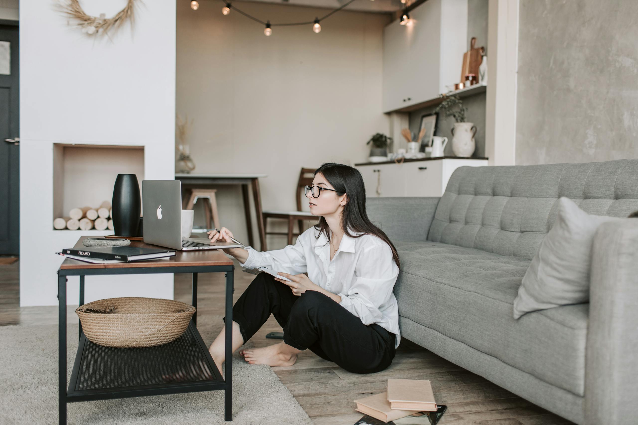 Asian woman working on laptop from cozy living room, showcasing modern home office setup.