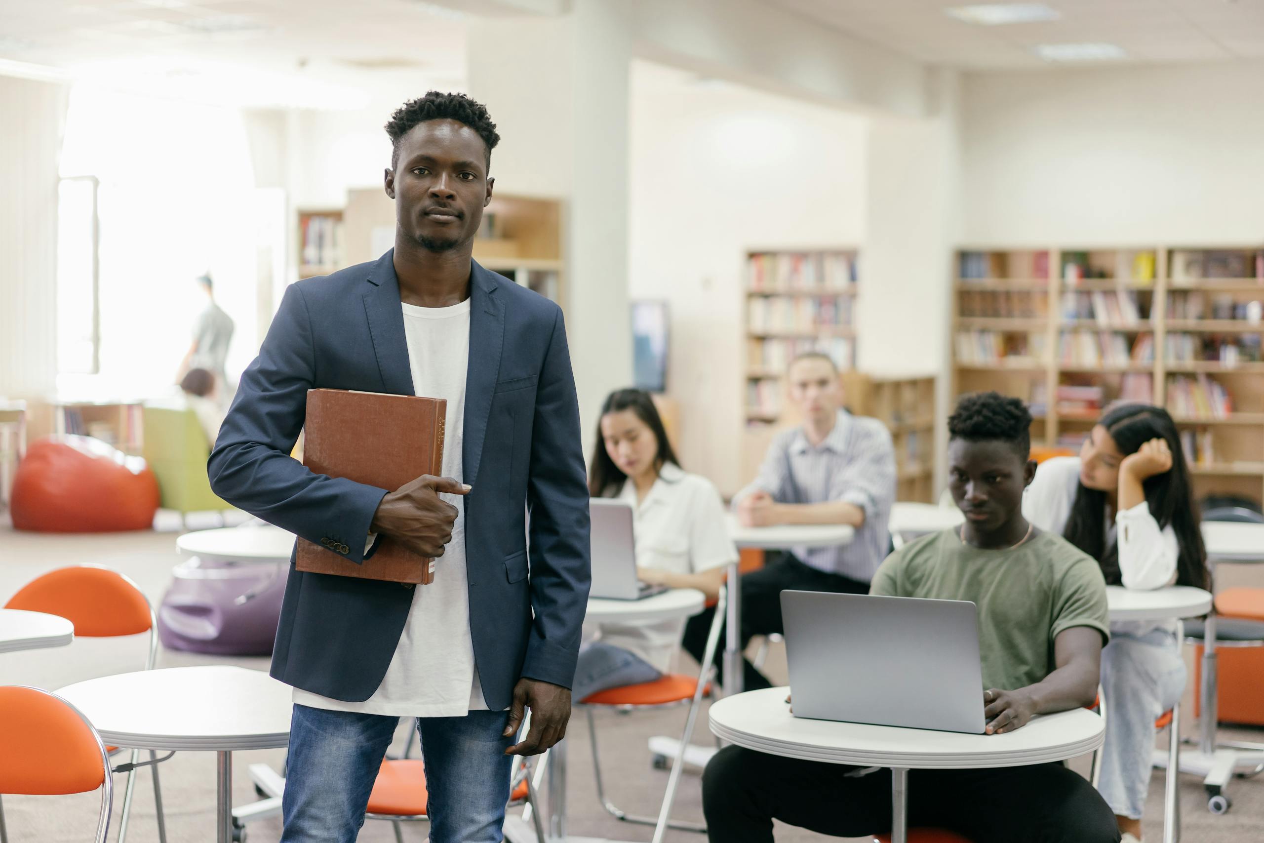 University library scene with students studying and professor present.